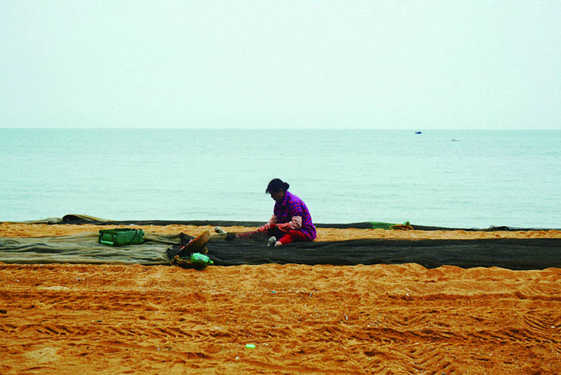 渔妇在沙滩边清理渔网.jpg